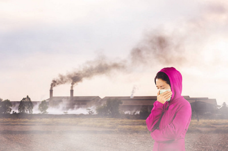 打喷嚏的女人穿着粉红色的冬衣，脸上戴着口罩，以防止空气污染