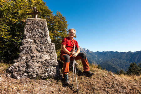 徒步旅行者坐在山顶上，对着镜头微笑。