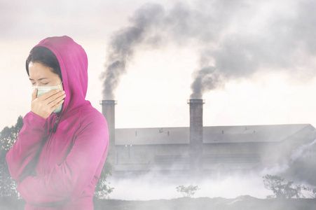 打喷嚏的女人穿着粉红色的冬衣，脸上戴着口罩，以防止空气污染
