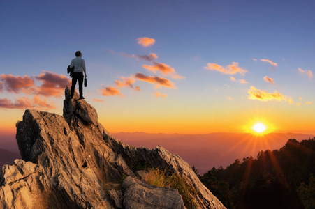 概念视野年轻商人穿着舒适的休闲西装外套,站在山顶上,手里拿着商务袋