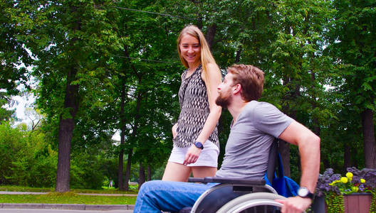 年轻的残疾人男子在公园散步与他的妻子