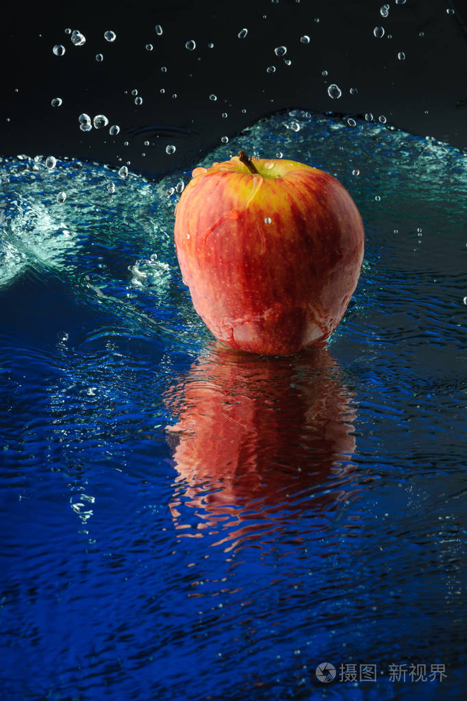 有倒影的苹果溅在蓝色背景上