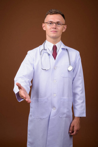 戴眼镜的年轻男子医生对棕色背景