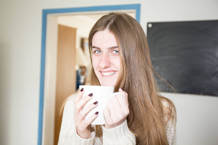 生活方式早晨的女孩，在家的厨房房间里的杯子里喝咖啡茶