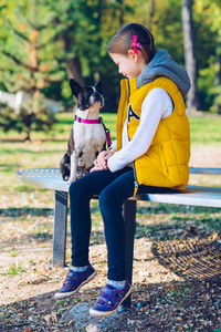 小女孩和波士顿猎犬在秋天的公园里玩耍。休闲时间概念