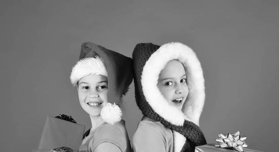 女孩们庆祝圣诞节。圣诞老人帽子与礼物的姐妹
