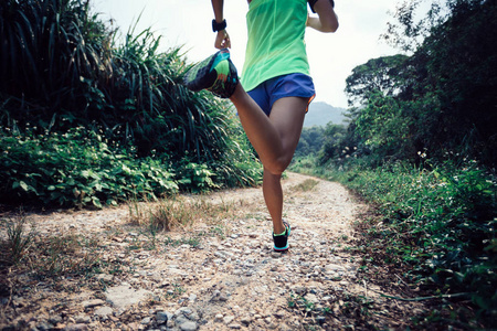 年轻的健身女子跑在森林道路上