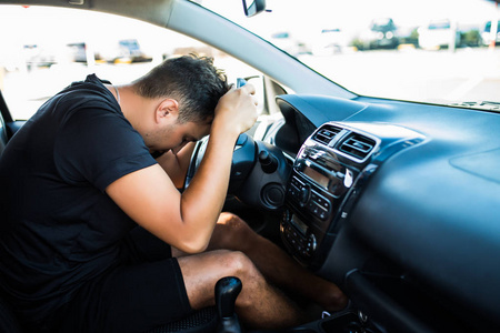 特写肖像疲惫的年轻英俊男子,短时间的注意力跨度驾驶他的汽车,经过长