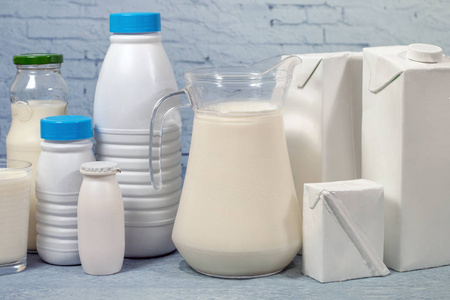 混合牛奶瓶和包装隔离在一个蓝色的砖背景.照片