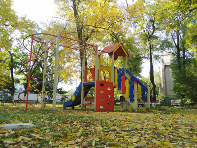 城市公园里的儿童游乐场，背景是落叶和秋树