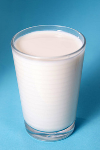 全杯牛奶隔离在蓝色背景上。