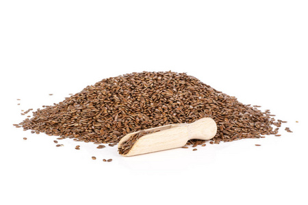 大量新鲜的棕色亚麻籽，用木勺隔离在白色背景上