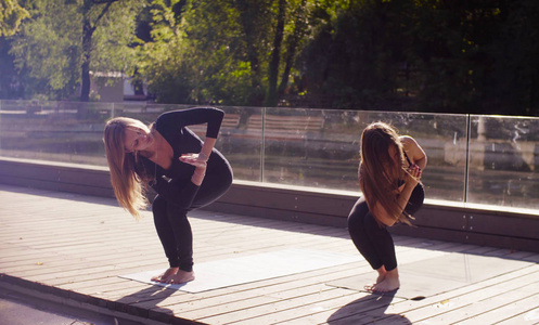 瑜伽。两个漂亮的女人在公园里做瑜伽健身操