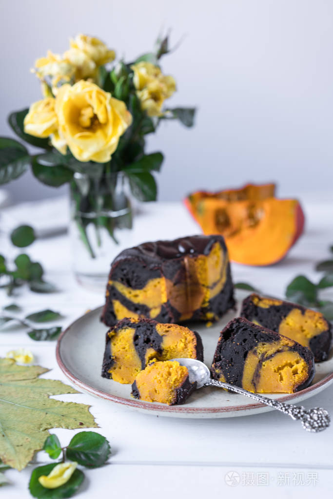 南瓜甜点和巧克力蛋糕,用绿叶装饰的白色乡村木制背景