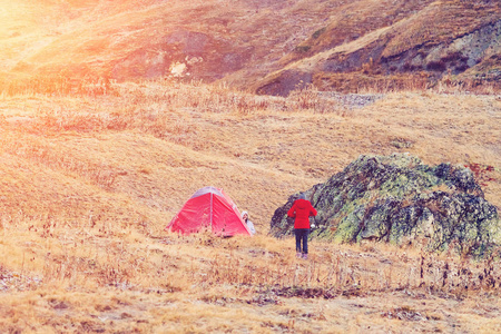 阳光明媚的一天，人们在山里的红色旅游帐篷附近