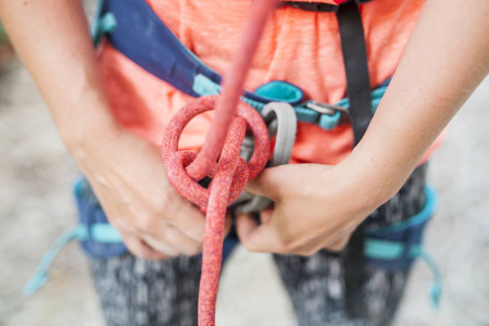 登山者编织一个结。 一个女人准备爬上一条攀岩路线。 攀岩的保险和安全。 安全绳。 节点8。