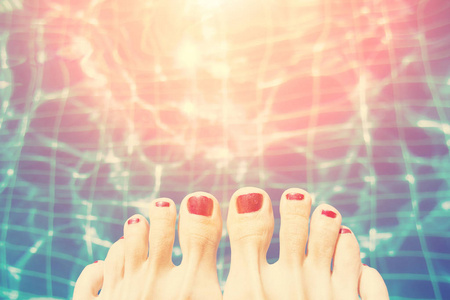 游泳池边有红色指甲油的女性脚
