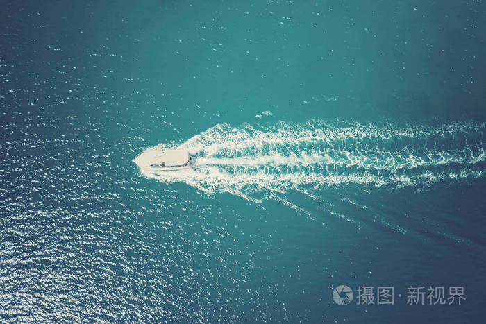 在蓝色大海中航行的白色小船的俯视图