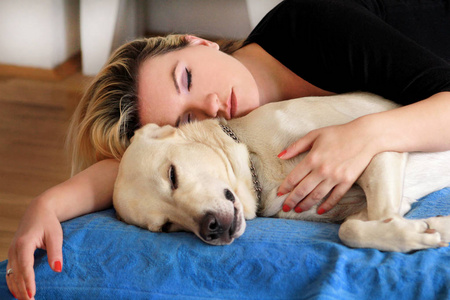 家里有可爱狗的女人。英俊的女孩和她的狗在卧室的床上休息和睡觉。主人和狗睡在沙发上。黄色拉布拉多猎犬放松。女人和她最好的朋友的肖像