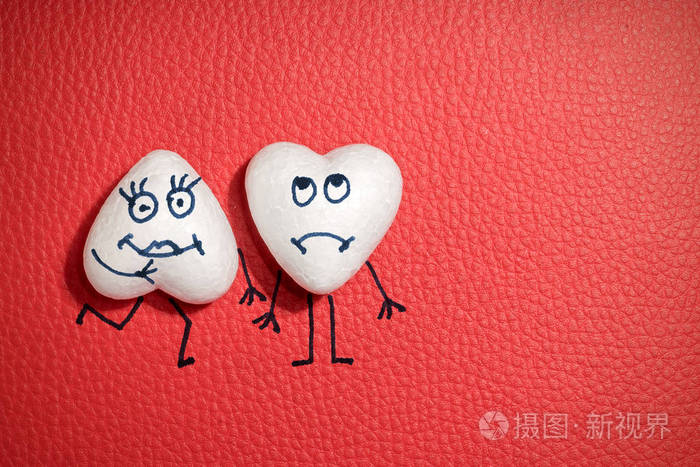 两颗白色的心红色的皮革背景上有快乐和悲伤的脸