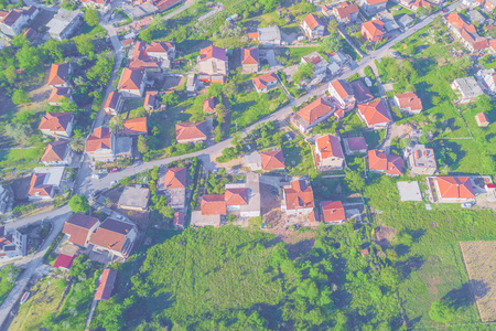 山顶上的村庄房屋有红色瓷砖屋顶在绿草上。划
