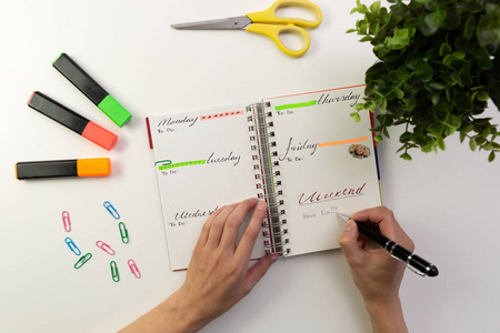 s hands with pen writing in planner. Modern  desk. Working