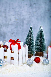 圣诞礼物和装饰品放在雪地上的白色盒子里，背景是肮脏的。 圣诞义卖。