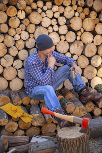 斧头在树桩上。 伐木工人坐在机器人后面休息。 斧头准备切割木材。木工工具。 伐木工人用斧头砍木材。 工人正在做斧头。 把斧子收起