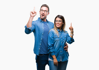 恋爱中的年轻夫妇戴着眼镜，在孤立的背景上指着手指，提出了成功的想法。 退出并快乐。 一号。