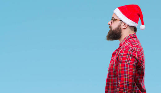 年轻的高加索人戴着圣诞帽，在孤立的背景下，看着侧面放松的轮廓，自然的脸，自信的微笑。