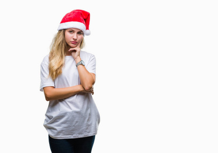 年轻漂亮的金发女人戴着圣诞帽，在孤立的背景下思考，看起来疲惫，厌倦了交叉双臂的抑郁问题。
