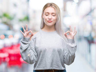 年轻的金发女子在孤立的背景下放松和微笑，闭着眼睛做冥想手势与手指。瑜伽概念。