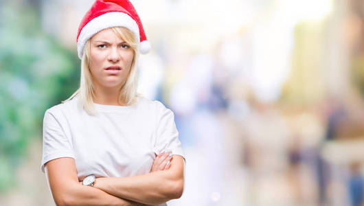 年轻漂亮的金发女人戴着圣诞帽，在孤立的背景怀疑和紧张，不赞成的表情在脸上交叉的手臂。消极的人。