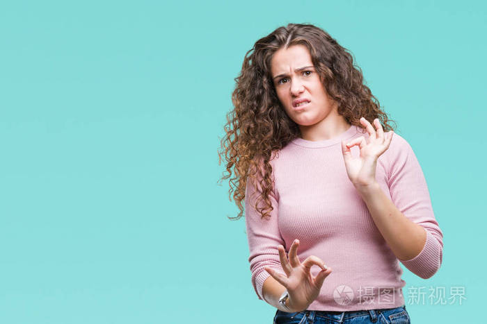 美丽的黑发卷发年轻女孩穿着粉红色毛衣在孤立的背景上厌恶表情不高兴