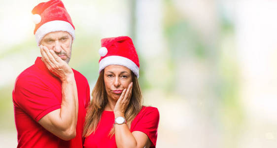 中年西班牙裔夫妇戴着圣诞帽，在孤独的背景下思考，看起来疲惫，厌倦了交叉双臂的抑郁问题。