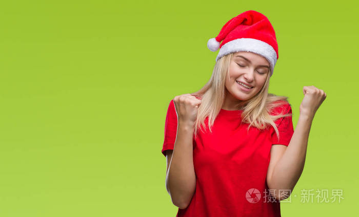 年轻的白种人妇女戴着圣诞帽,在孤立的背景下,非常高兴和兴奋地做着