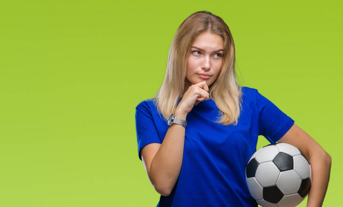 年轻的白种人女人抱着足球在孤立的背景下严肃的面对思考问题，非常困惑的想法