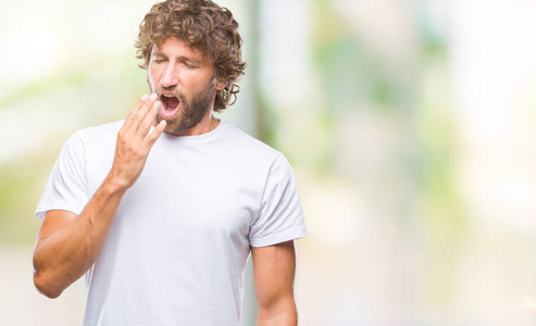 英俊的西班牙裔模特男子在孤立的背景下无聊地打哈欠，疲惫地用手捂住嘴。 不安和困倦。