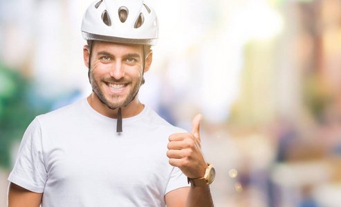 年轻的帅哥戴着自行车安全头盔，在孤立的背景下，用手做快乐的拇指向上的手势。 赞许的表情看着相机，显示出成功。