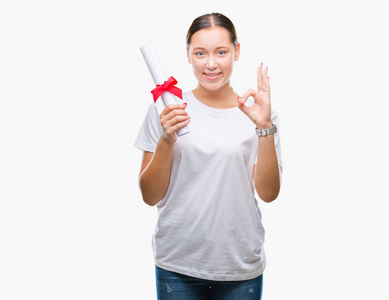 年轻的白种人妇女在孤立的背景下持有学位，用手指做OK标志，优秀的符号