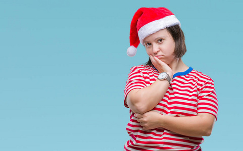 年轻的成年妇女患有唐氏综合症，戴着圣诞帽，在孤立的背景下思考，用交叉的手臂看起来疲惫，厌倦了抑郁的问题。