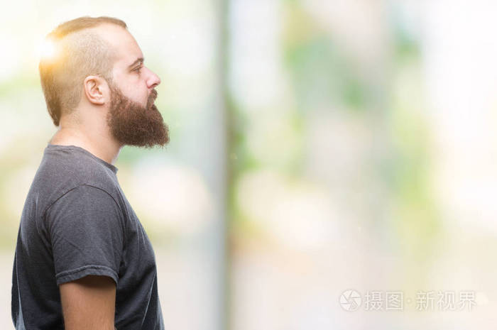 年轻的白种人潮男在孤立的背景下,看着侧面放松的轮