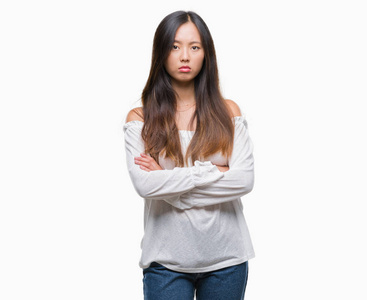年轻的亚洲女人超过孤立的背景怀疑和紧张的不赞成的表情在脸上交叉的手臂。 消极的人。