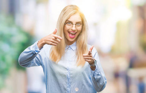 年轻漂亮的金发商务女性戴着眼镜，戴着孤立的背景，手指指向相机，脸上带着快乐和有趣的表情。 良好的能量和氛围。