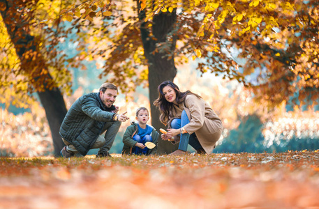 年轻的家庭和他的儿子在秋天公园玩得很开心。