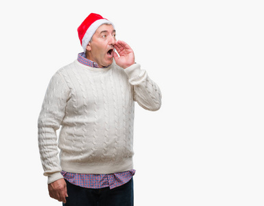 英俊的老人戴着圣诞帽，在孤立的背景上大声喊叫，并大声尖叫，手在嘴上。 交流概念。