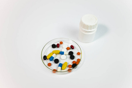 玻璃碗中的各种药丸和白色背景上的塑料瓶