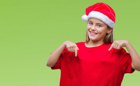 年轻漂亮的女孩戴着圣诞帽，戴着孤立的背景，脸上带着，用手指指着自己，骄傲和快乐。
