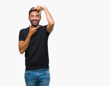 成年西班牙裔男子在孤立的背景上微笑，用手和手指制作框架，用快乐的脸。 创造力和摄影理念。