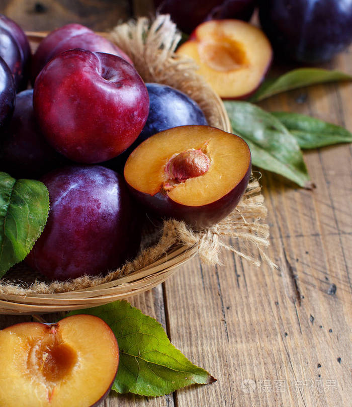 木桌上放着叶子的新鲜李子照片-正版商用图片13nx7c-摄图新视界